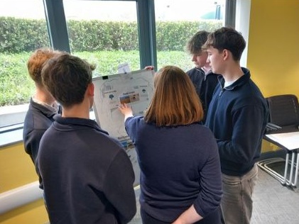 A group of people looking at information on a white board.